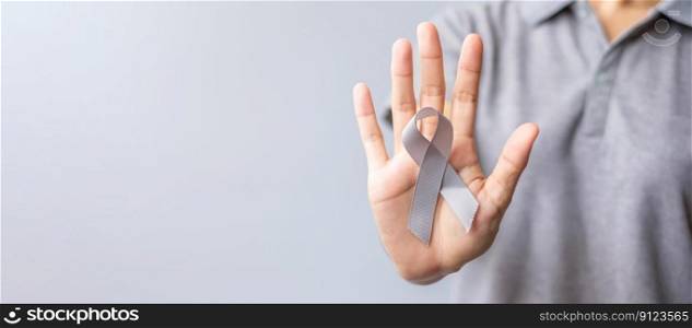 Brain Cancer Awareness month, woman hand holding grey color Ribbon for supporting people life. Healthcare and World cancer day concept