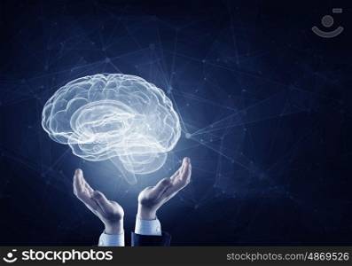 Brain in male hands. Hands on dark background holding with care brain glowing symbol
