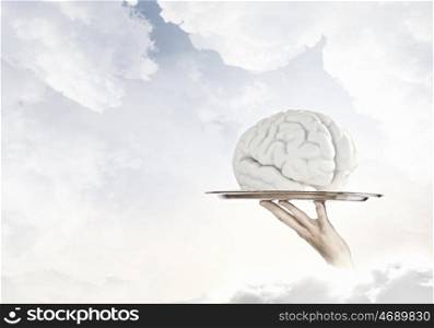 Brain on metal tray. Hand holding metal tray with human brain symbol