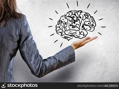 Brainstorming and analyzing. Rear view of businesswoman holding brain on palm
