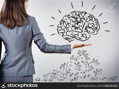 Brainstorming and analyzing. Rear view of businesswoman holding brain on palm