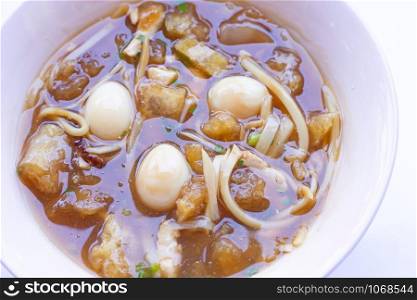 Braised fish maw in red gravy in bowl on white background.