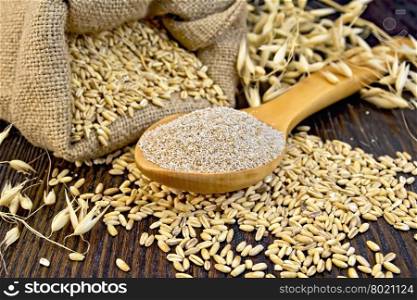 Bran flakes oat in spoon, a bag of grain oats, oat ears against the dark wooden board