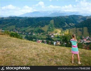 Bran village summer view (near Brasov, Romania) and girl on slope.