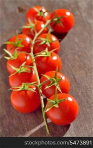 Branch of cherry tomatoes isolated on wooden table