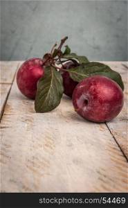 Branch of delicious red plums on a wooden background