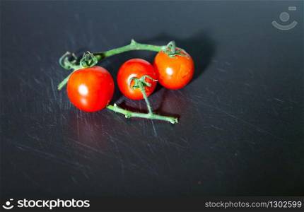 Branch of fresh red cherry tomatoes isolated on the board. Branch of tomatoes
