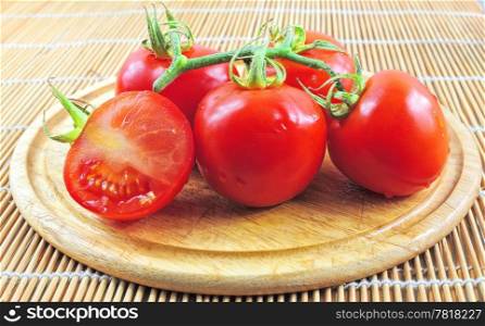 Branch of fresh tomatoes on wooden board