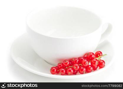 branch of red currants and a cup with a plate isolated on white