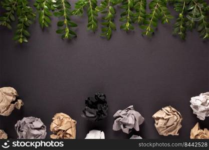 Branch with leaf and crumpled paper balls at black background texture. Ecology concept or creative idea