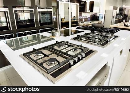 Brand new gas stoves and ovens for sale. Rows of brand new gas stoves and ovens with stainless steel trays in appliance retail store