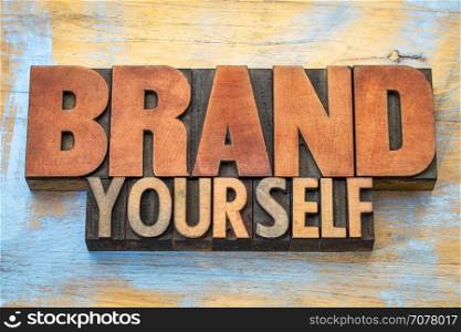Brand yourself - word abstract in vintage letterpress wood type blocks against grunge wooden background