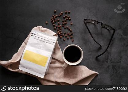 Branding identity of coffee beans and hot cup of black coffee drink with eyeglasses on stone background, business and mockup concept