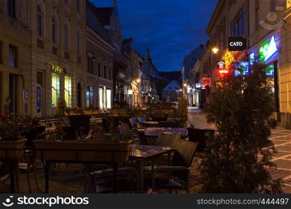 BRASOV, ROMANIA NOVEMBER 1, 2017: view of the street cafe on the main square in the historic city center Brasov illuminated by the street lamps. BRASOV, ROMANIA, November 1, 2017