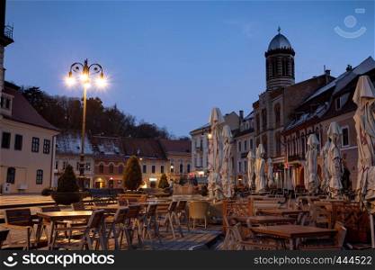 BRASOV, ROMANIA NOVEMBER 1, 2017: view of the street cafe on the main square in the historic city center Brasov at dawn. BRASOV, ROMANIA, November 1, 2017