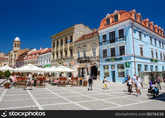 Brasov, Transylvania, Romania, 6th July 2015: Council Square is historical center of city, people walkinng and sitting at outdoor terraces and restaurants.