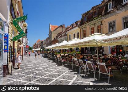 Brasov, Transylvania, Romania, 6th July 2015: Republic street is par of pedestrian area in historical center of city, people walkinng and sitting at outdoor terraces and restaurants.