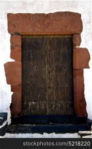brass brown knocker in a brown closed wood door and white wall lanzarote abstract spain canarias