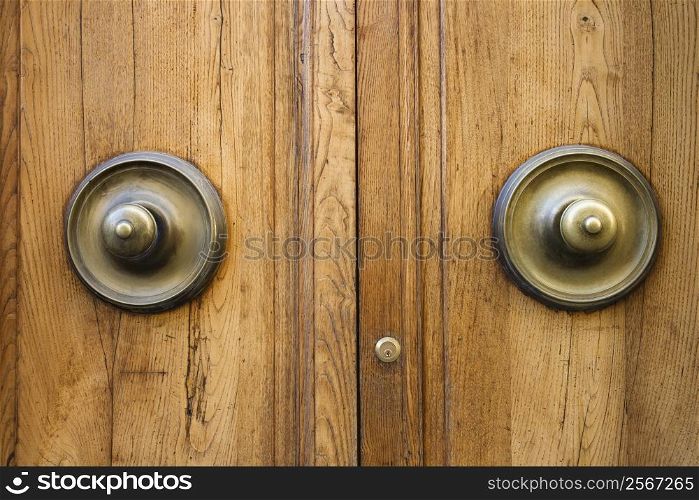 Brass doorknobs on wooden door with lock.