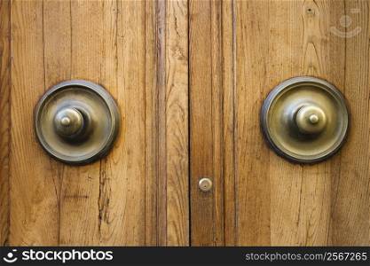 Brass doorknobs on wooden door with lock.