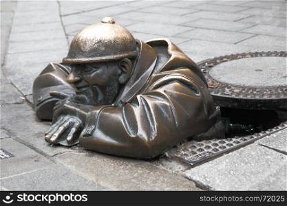 BRATISLAVA, SLOVAKIA - JUNE 25, 2014: Cumil (The Watcher) - famous statue of man peeking out from under a manhole cover. It was made in 1997 by Viktor Hulik