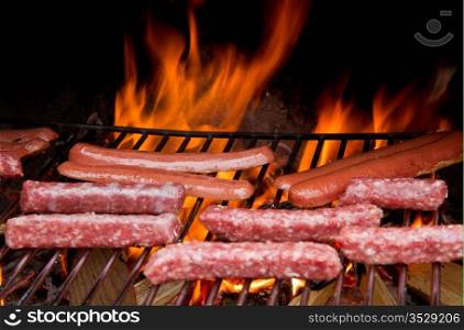 Brats cooking on the grill with a flame in the background