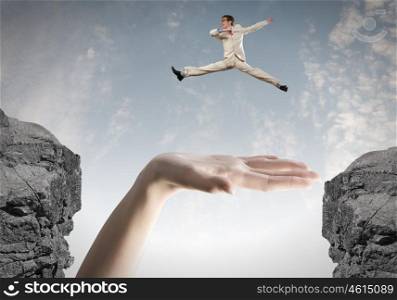 Brave businessman. Young businessman in suit jumping over mountain gap