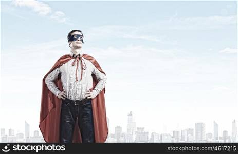 Brave superhero. Young confident superman in mask and cape