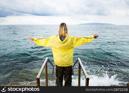 Brave woman greeting stormy ocean