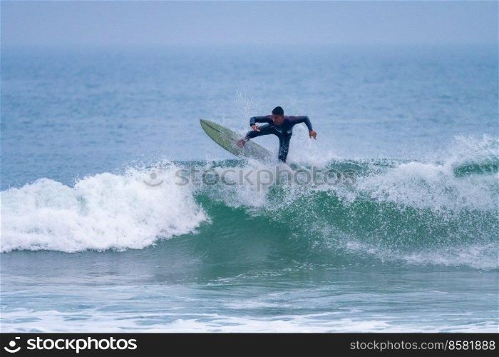 Brazilian surfer in action in the waves of the Atlantic coast of Portugal. On a cloudy morning at Furadouro beach, Ovar - Portugal.