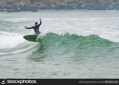 Brazilian surfer in action in the waves of the Atlantic coast of Portugal. On a cloudy morning at Furadouro beach, Ovar - Portugal.