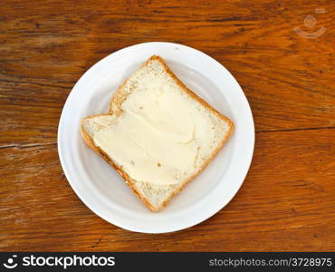 bread and butter sandwich on white plate on wooden table