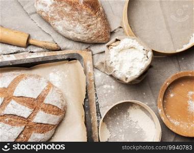 bread and  white wheat flour in a bag, wooden rock and plate, top view