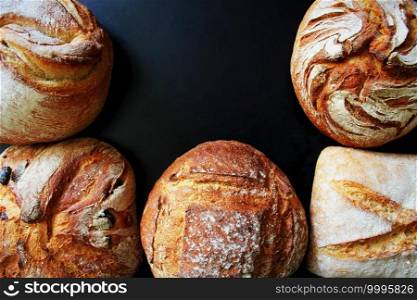 Bread. Assortment of different types of bread on a blackn background. Loaf, bun, baguette, cereal bread. Bakery products.