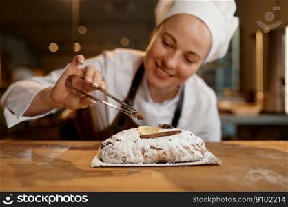 Bread bakery worker wearing uniform and apron decorating diet wheat loaf or bun while standing at modern kitchen. Bread bakery worker decorating diet wheat loaf or bun