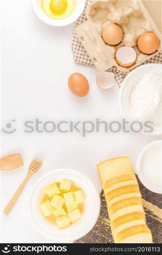 bread concept a wooden spatula, cubes of butter in the bowl, eggs, slices of bread, and a bowl of flour organized on the light scene.