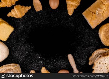 bread concept slices of bread, buns, croissants, and loaves of bread arranged in circle on the black scene and sprinkling flour dust on it.