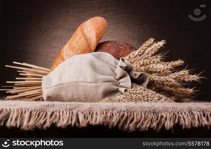 Bread, flour sack and ears bunch still life on rustic background