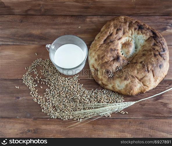 Bread, milk and wheat on a wooden background