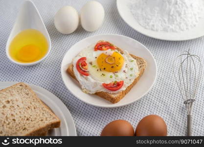 Bread placed with a fried egg with tomatoes, tapioca flour and sliced   spring onions.