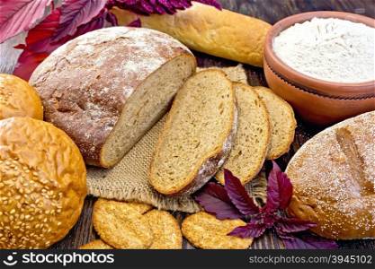 Bread, rolls and biscuits, amaranth flour in a clay bowl, purple amaranth flower on the background of wooden boards