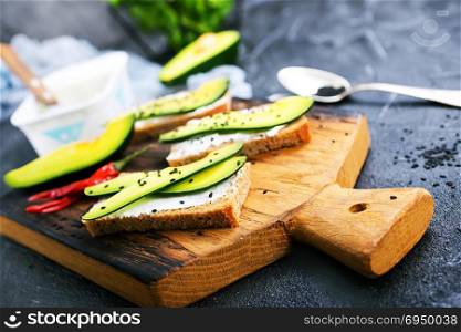 bread with cheese and with avocado on wooden board