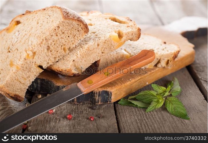 Bread with knife on a cutting board and wooden background