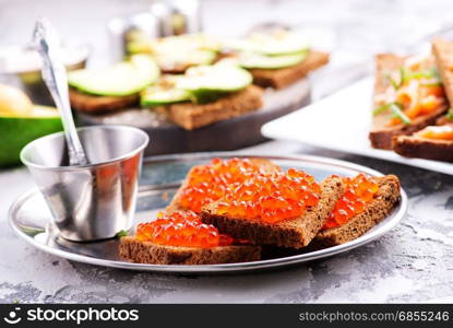 bread with red salmon caviar on a table