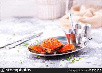 bread with red salmon caviar on metal plate