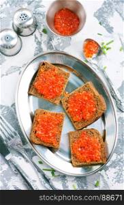 bread with red salmon caviar on metal plate