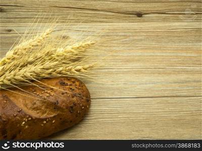 Bread with sesame seeds and ears on a wooden background.