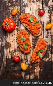 Bread with tomato spread on rustic wooden background, top view. Vegetarian food concept.