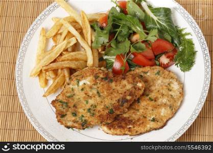 breaded chicken schnitzels or escalopes with french fries and a tomato and green salad