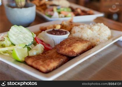 Breaded chicken with salad on wooden table with COPY SPACE, Close up of chicken fillet with salad, rice and beans